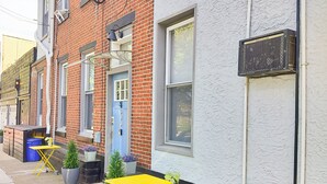 A row of brick buildings with a blue door, outdoor seating, and potted plants. - Cozy Vibe MicroFlat with AC, W/D, FastWiFi in the heart of Fishtown Philadelphia (Philadelphia)