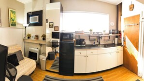A compact kitchen with a microwave, coffee maker, and sink. There is a small refrigerator and a chair in the adjacent living area. - Cozy Vibe MicroFlat with AC, W/D, FastWiFi in the heart of Fishtown Philadelphia (Philadelphia)