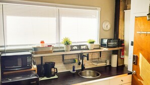 A compact kitchen with a microwave, coffee maker, sink, and a clock on the wall. - Cozy Vibe MicroFlat with AC, W/D, FastWiFi in the heart of Fishtown Philadelphia (Philadelphia)