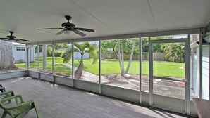 A covered patio with ceiling fans, large windows, and a view of a well-maintained lawn. - Charming Bradenton getaway on the Gulf Coast - Flip Flop Retreat (Bradenton)