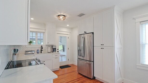 A modern kitchen with white cabinetry, stainless steel appliances, and a wooden floor. - Charming Bradenton getaway on the Gulf Coast - Flip Flop Retreat (Bradenton)