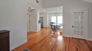 A spacious kitchen with wooden flooring, white cabinets, and a dining area with chairs and a table. - Charming Bradenton getaway on the Gulf Coast - Flip Flop Retreat (Bradenton)