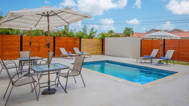A backyard with a swimming pool, lounge chairs, and a table with an umbrella. - Hello Summer! 2BR Home w/ Pool, 5min Walk to Reduit Beach, Dining & Nightlife in Rodney Bay! (Rodney Bay)