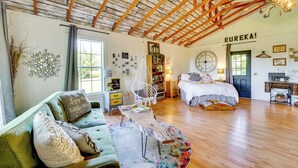 A cozy bedroom with a bed, a green sofa, a wooden coffee table, and a wall-mounted circular mirror. - 1 Mi to Downtown Eureka Springs: Studio Retreat (Eureka Springs)