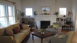 A living room with a sofa, armchairs, a coffee table, and a fireplace. - Classic Ann Arbor Home Near Stadium and Campus (Ann Arbor)