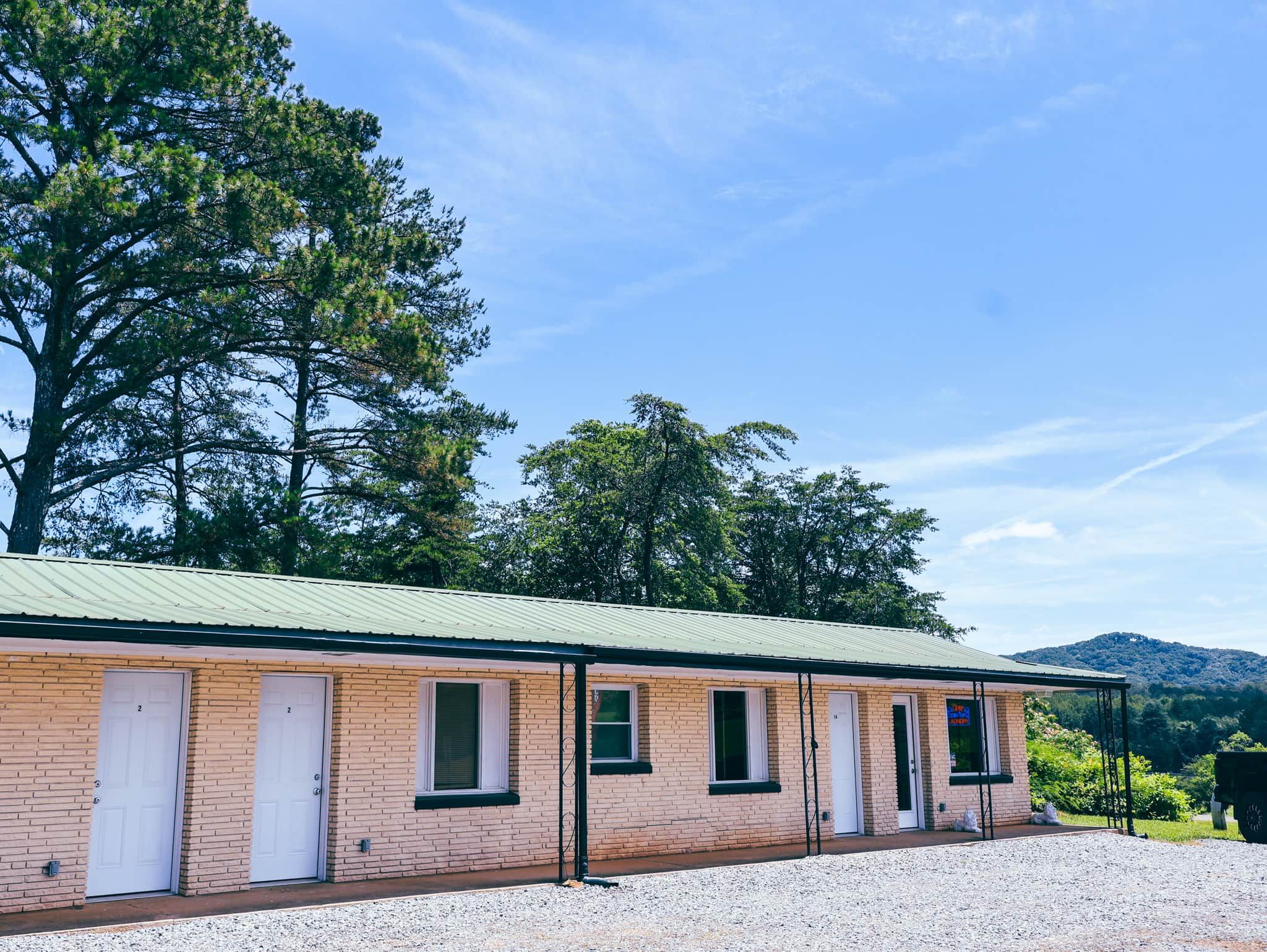 Un edificio de ladrillo de dos pisos con techo verde, múltiples ventanas y un camino de entrada de grava.
