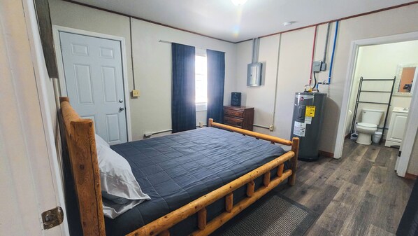 A bedroom with a wooden bed, a wardrobe, a heater, and a bathroom with a toilet and sink.