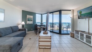 Un ampio soggiorno con vista sulla spiaggia, una zona pranzo e un balcone panoramico.