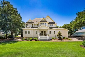 A two-story house with a front porch, a small front yard, and a well-maintained lawn.