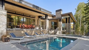 Une maison moderne dotée d’une piscine, de piliers en pierre et d’un espace salon extérieur.