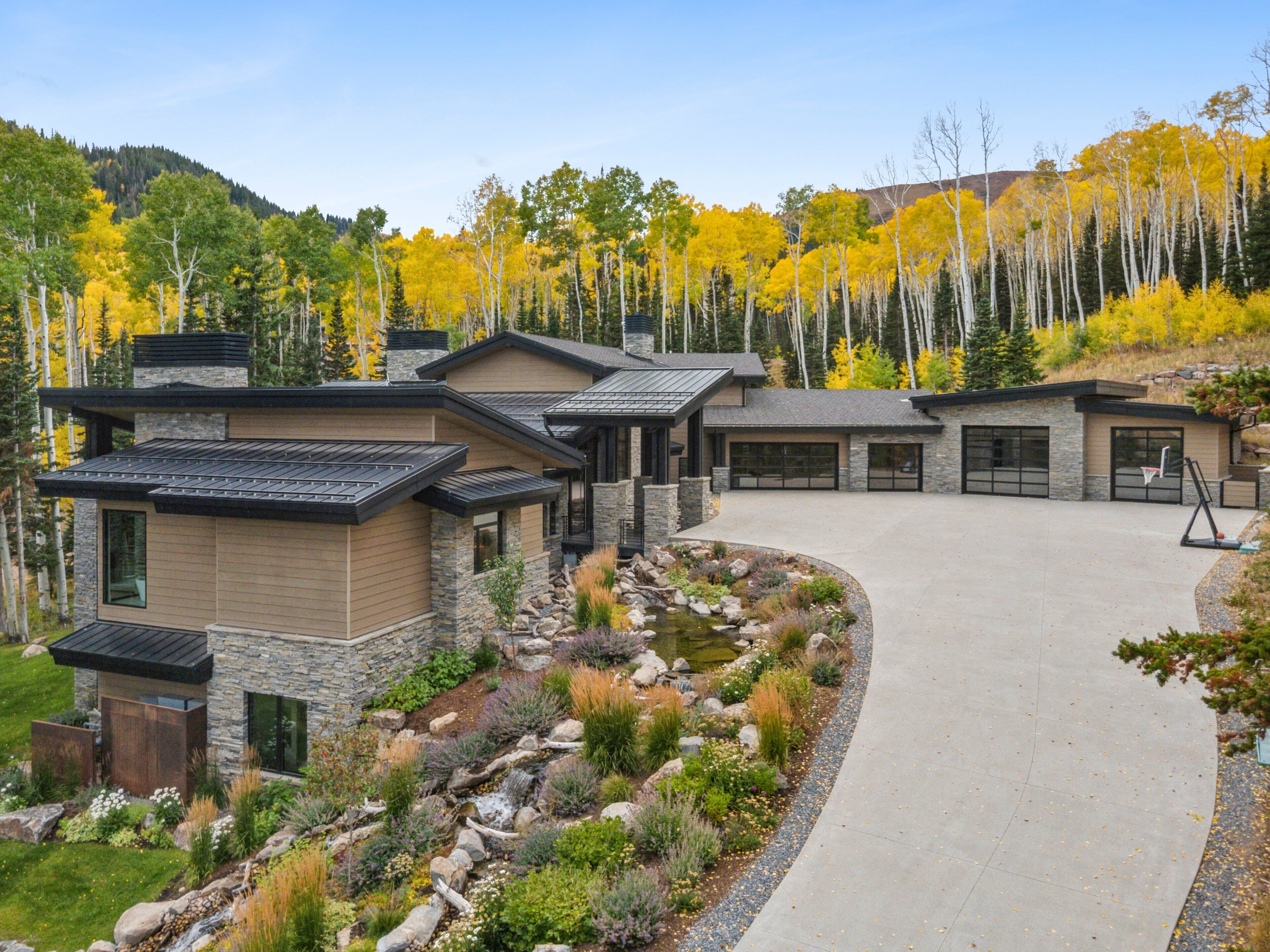 A modern house with a stone facade, multiple garage doors, and a landscaped driveway.