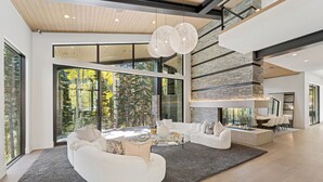 Un salon moderne doté d’une cheminée, de grandes fenêtres et d’un mur d’accent en pierre.