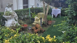 A house with a balcony, a garden with potted plants, and a statue. - Accommodation Belo Horizonte (Alfena)