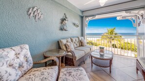 Una stanza con vista sull'oceano, un ventilatore a soffitto e un balcone con ringhiera.