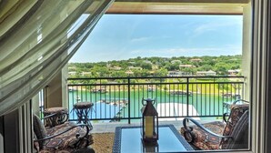 Un balcón con mobiliario de mimbre, una mesa y vista a un campo de golf y una masa de agua.
