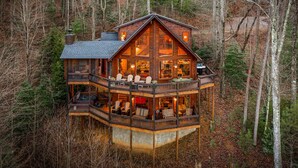 A multi-level wooden cabin with a balcony, surrounded by trees. - Grandeur View Lodge - Mountain View | Hot Tub | Game Room (Blue Ridge)