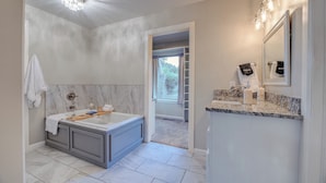 Ein modernes Badezimmer mit Marmor-Waschtisch, einer großzügigen Badewanne und einem begehbaren Kleiderschrank.