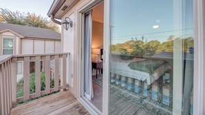 Ein Schlafzimmer mit einer Schiebetür, einer Holzterrasse und Blick auf den Garten.
