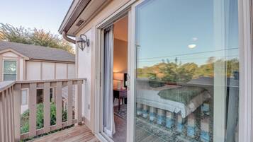 A bedroom with a sliding glass door, a wooden deck, and a view of the backyard.