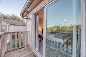 A bedroom with a sliding glass door, a wooden deck, and a view of the backyard. - Heated Pool, 3 King Bedrooms- 2 Suites, Sleeps 14, Private Backyard Near OU (Norman)