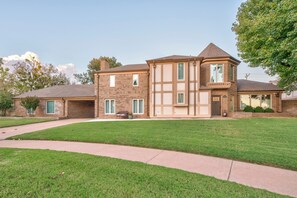 A two-story house with a brick facade, a front porch, and a well-maintained lawn.