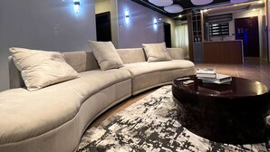 A modern living room with a curved sofa, a round coffee table, and a patterned rug. - Luxury 3-Bedroom Home in Maitama Abuja (Abuja)