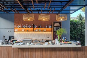 A modern bar area with a wooden counter, various beverage dispensers, and a selection of plates and glasses. - Oase Resort Bandung (Parongpong)