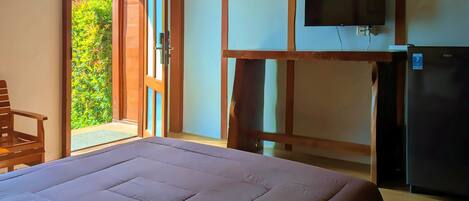 A bedroom with a bed, a television mounted on the wall, and a refrigerator.