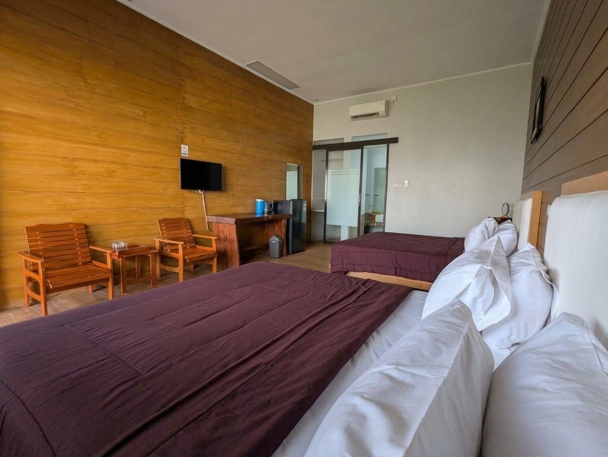 Une chambre d’hôtel avec deux lits, une télévision, un bureau et une chaise.