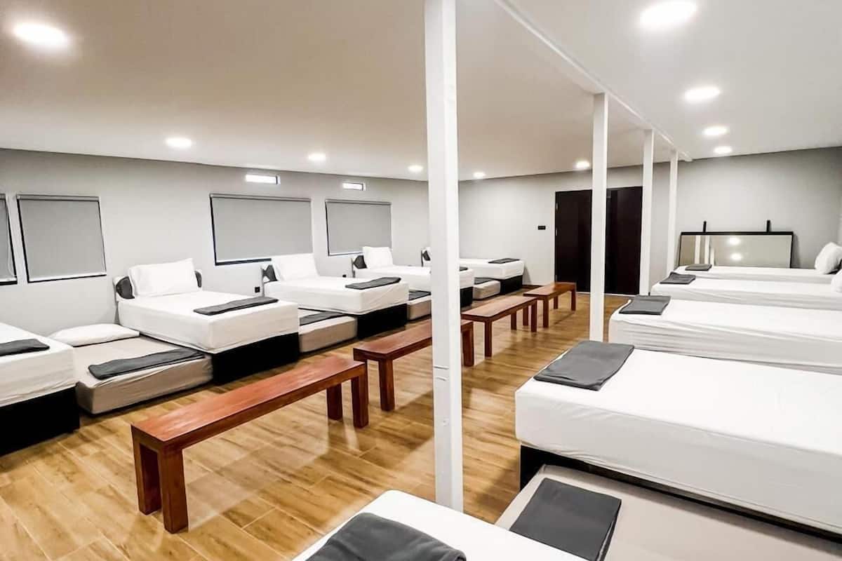 Een hotelkamer met meerdere bedden, houten bankjes en een modern design.