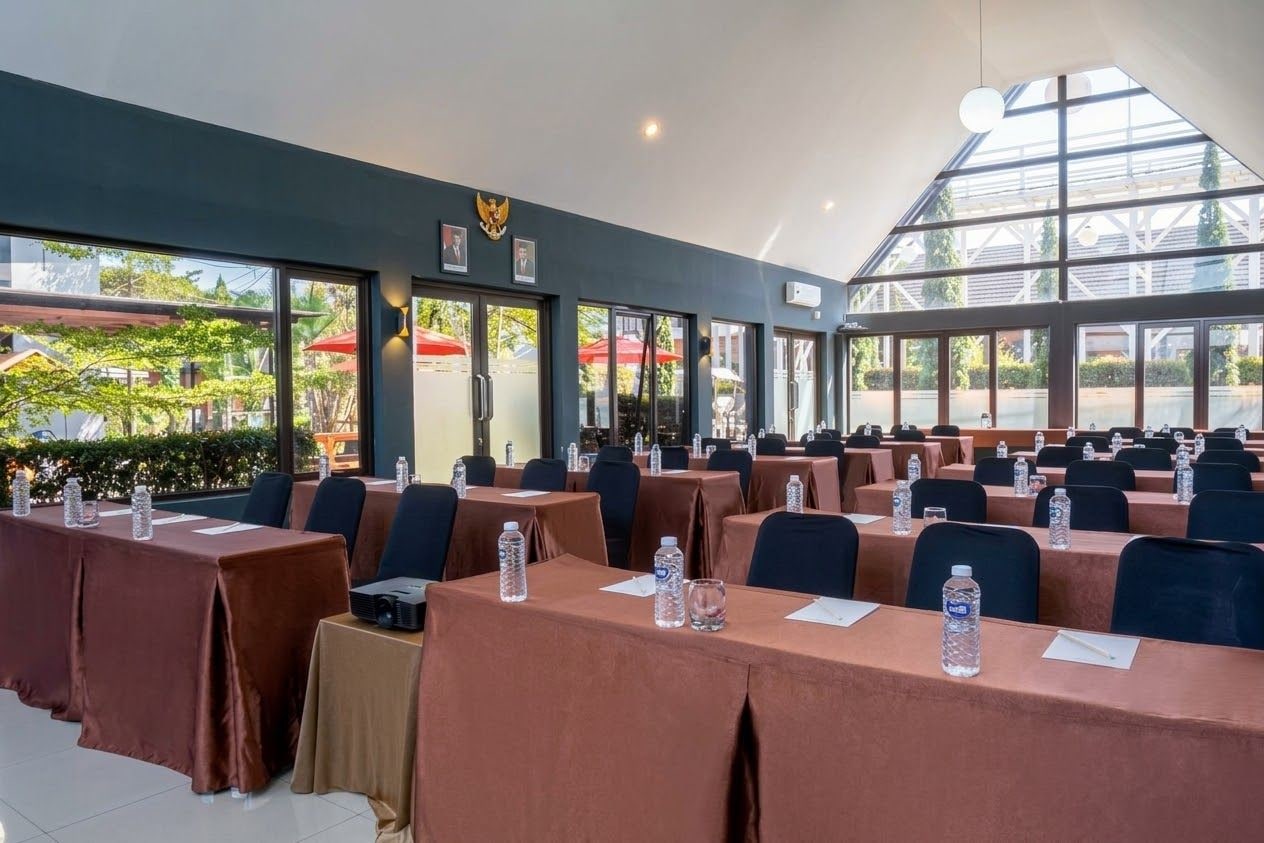 Un salón de conferencias con mesas, sillas y botellas de agua.