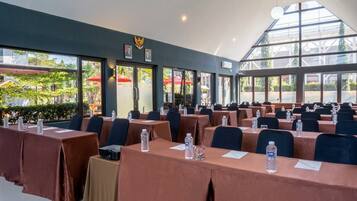 Un salón de conferencias con mesas, sillas y botellas de agua.