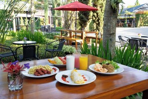 An outdoor dining area with tables, chairs, and a variety of food and drinks. - Oase Resort Bandung (Parongpong)