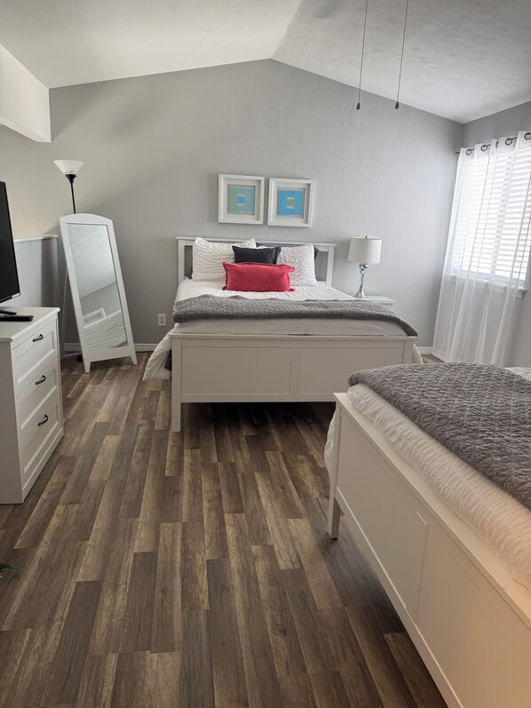A bedroom with a bed, a dresser, a mirror, and two framed pictures on the wall.