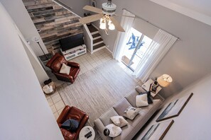 A spacious living area with a staircase, a sofa, a coffee table, and a television.