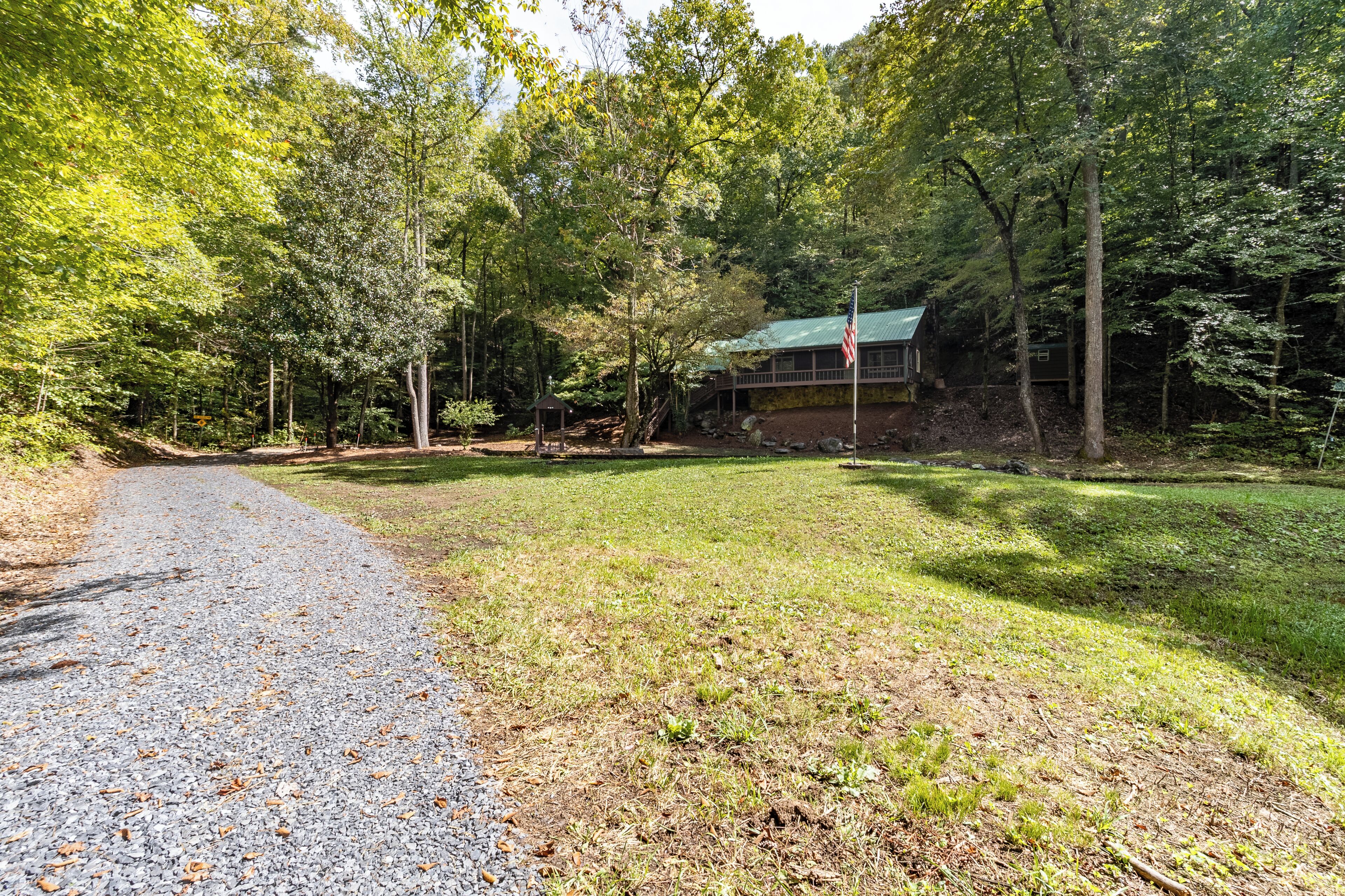 A cabin with a green roof, surrounded by dense forest.