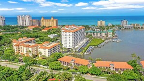 A coastal cityscape with high-rise hotels, a marina, and lush greenery. - Bayfront Bliss Near Vanderbilt Beach (Naples)