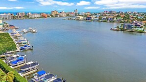 A marina with boats docked, a cityscape in the background, and a clear sky. - Bayfront Bliss Near Vanderbilt Beach (Naples)