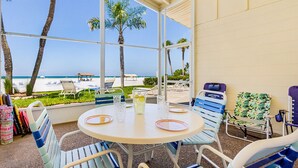 A beachside patio with a round table, chairs, and a view of the ocean. - Combined Beachfront Bliss - Aloha Kai #24 & #24N - Roelens (Siesta Key)