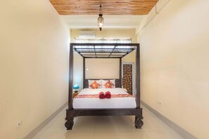 A four-poster bed with a canopy, a nightstand with a lamp, and a decorative wall panel. - Griya Agung Guesthouse Ubud (Ubud)