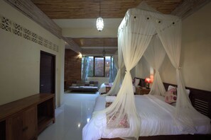 A bedroom with a four-poster bed, a wooden ceiling, and a view of the outside through a window. - Griya Agung Guesthouse Ubud (Ubud)