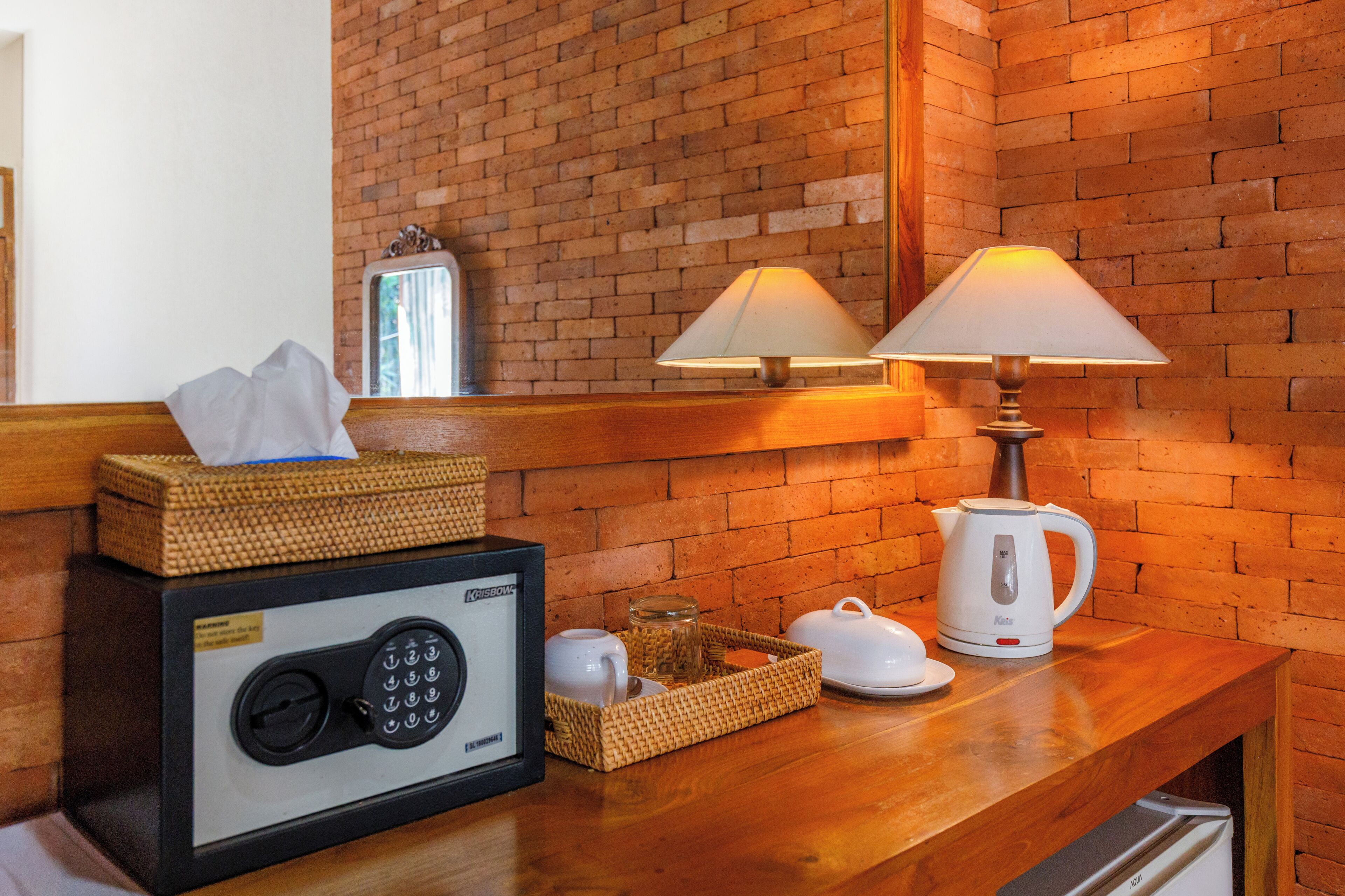 A wooden bench with a safe, a lamp, a kettle, and a basket with a tissue box.