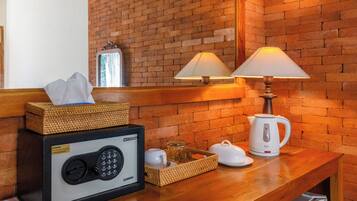 A wooden bench with a safe, a lamp, a kettle, and a basket with a tissue box.