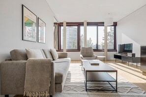 Un salon moderne comprenant un canapé, un fauteuil, une table basse et un téléviseur à écran plat.