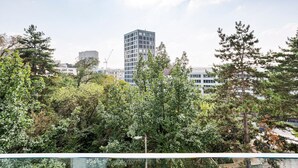 Ein modernes Gebäude mit Glasfassade, umgeben von üppiger Vegetation und weiteren Gebäuden im Hintergrund.