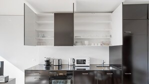 Eine moderne Küche mit dunklen Schränken, einem Einbauofen, einer Mikrowelle, einer Kaffeemaschine und einem Toaster.