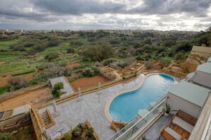 A rooftop pool with a view of a residential area and distant buildings.