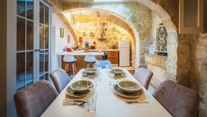 Comedor con arco de piedra, cocina al fondo y vista al exterior.