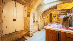 Una cocina rústica con paredes de piedra, una encimera de madera y un comedor con una mesa dispuesta para dos.