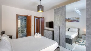 Una camera da letto moderna con un letto grande, una televisione e un cabina armadio con uno specchio.